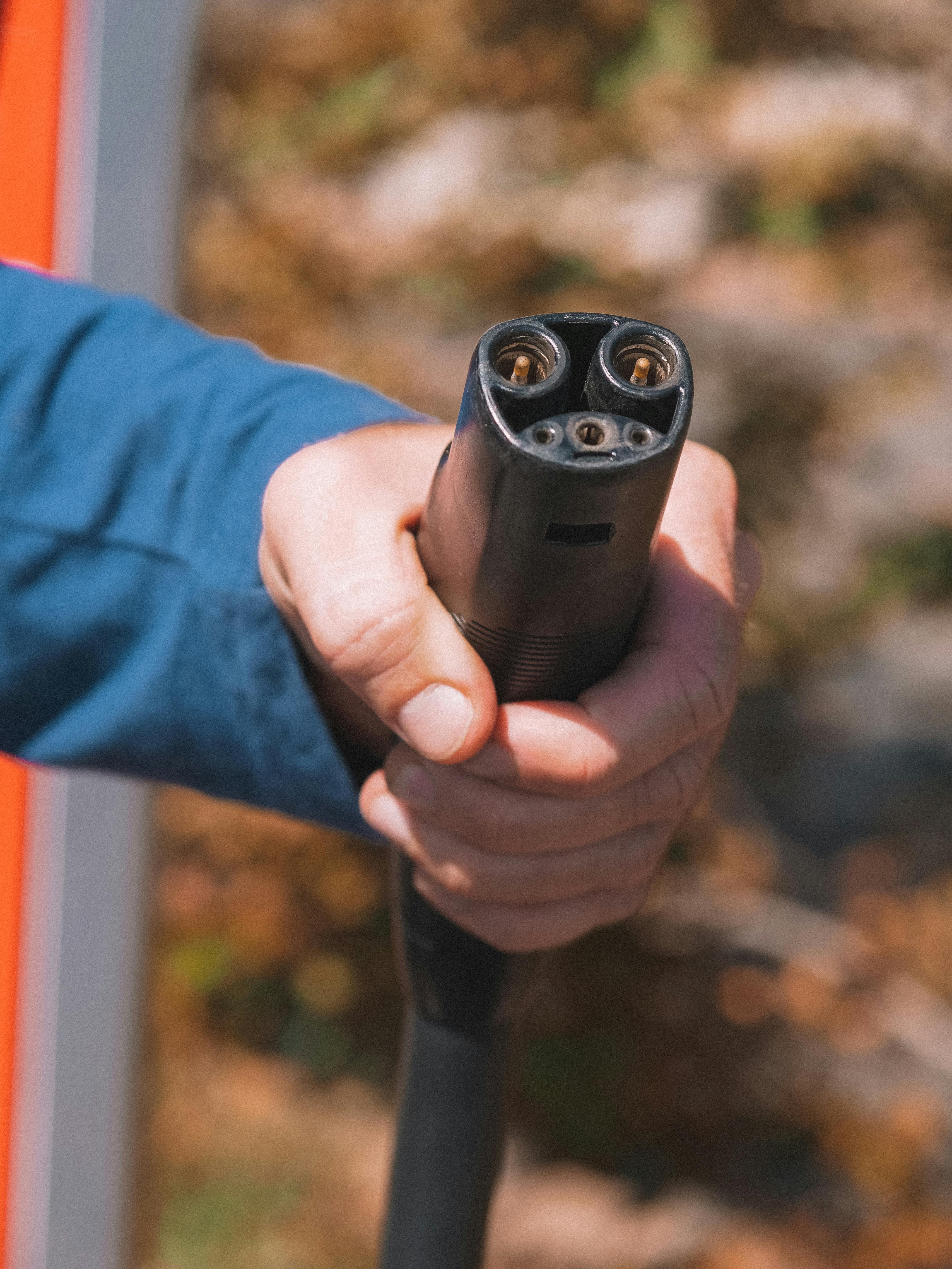 A person holding an electric car charger. 
