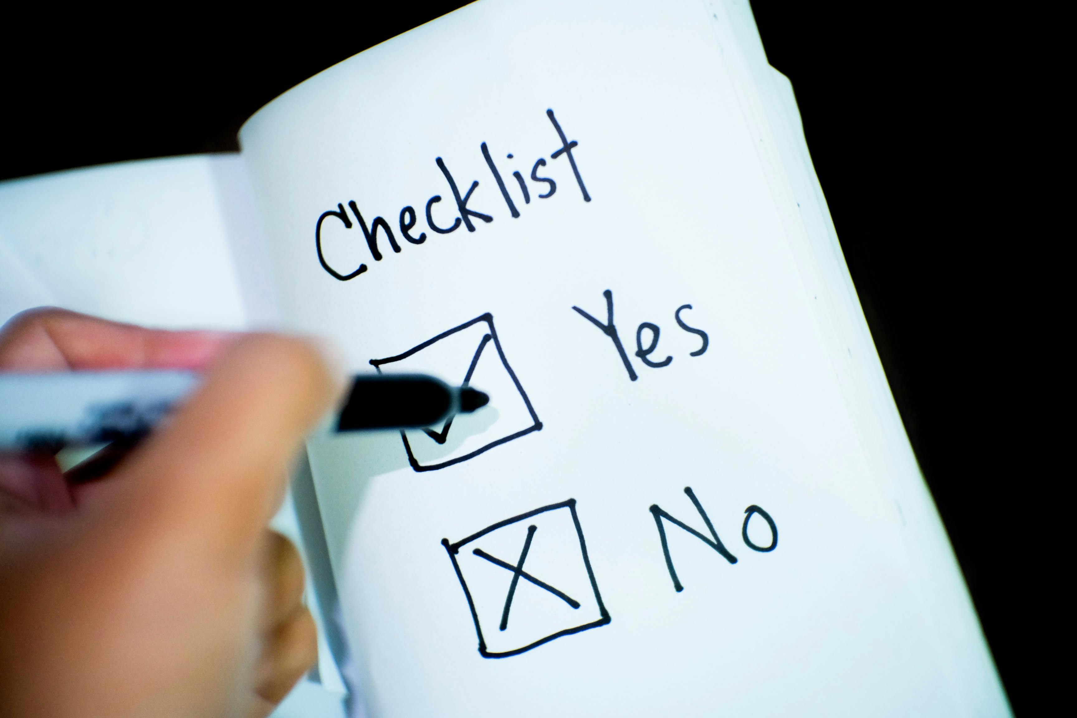 A checklist on paper where a person is marking with a pen